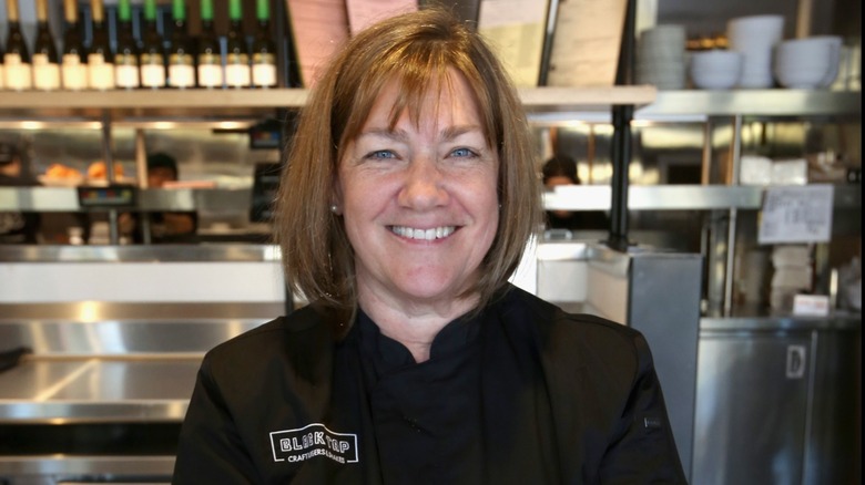 Chef Gale Gand smiling at the camera in an industrial kitchen