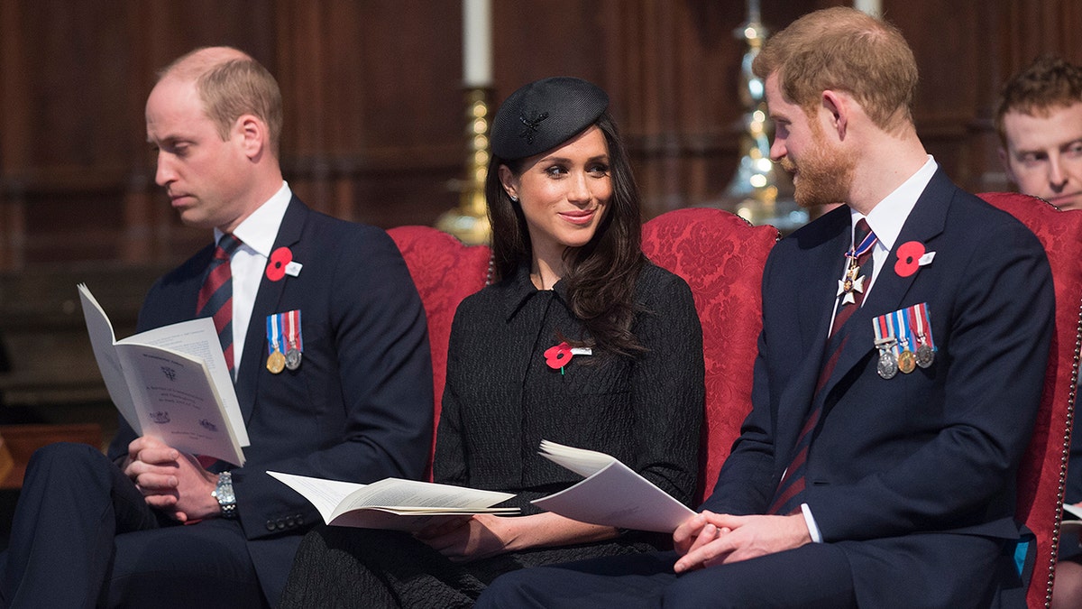Prince William looking away as Meghan Markle and Prince Harry smile at each other sitting in church.
