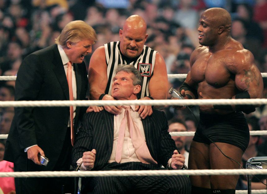 A snarling Vince McMahon, in a suit with pink necktie askew, sits in a wrestling ring with Stone Cold Steve Austin in a sleeveless referee shirt standing behind him and restraining him. McMahon gazes up and to the viewer's left, looking at Donald Trump in a suit, who is sneering open-mouthed while holding electric clippers in his right hand. To the viewer's right is Bobby Lashley, shirtless and heavily muscled and also holding clippers. 