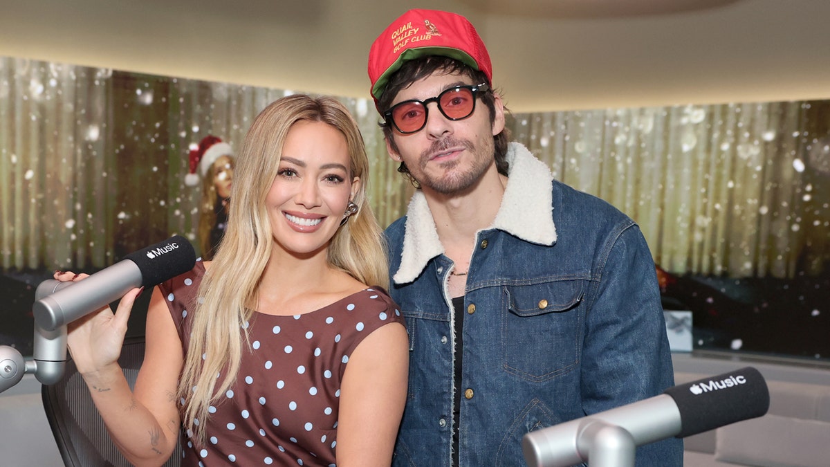 Hilary Duff and Matthew Koma sitting at microphones in a radio studio.