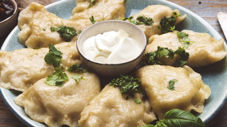 A plate of pierogies surrounding a small bowl of sour cream