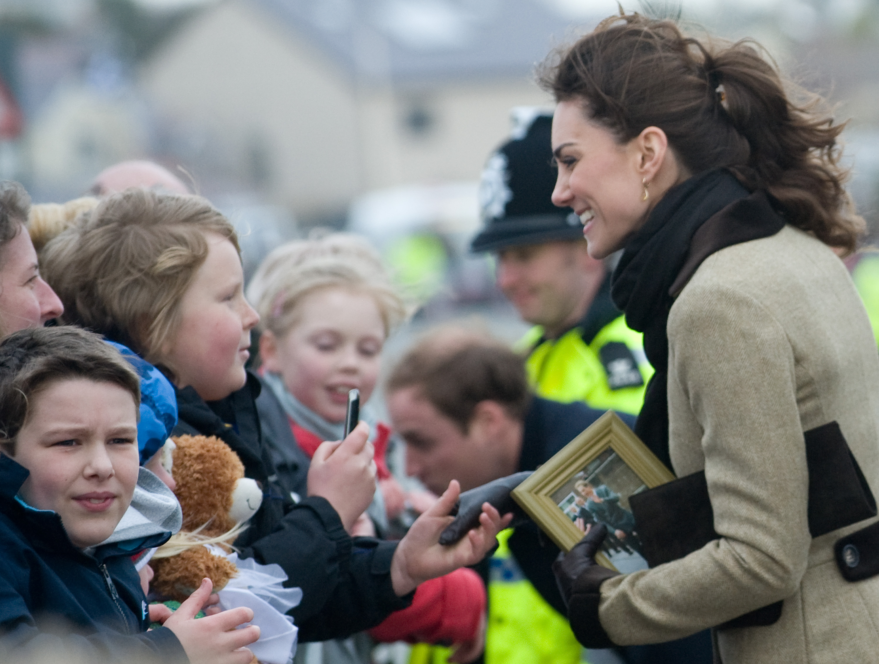 Kate Middleton greeting fans holding a framed photo of William