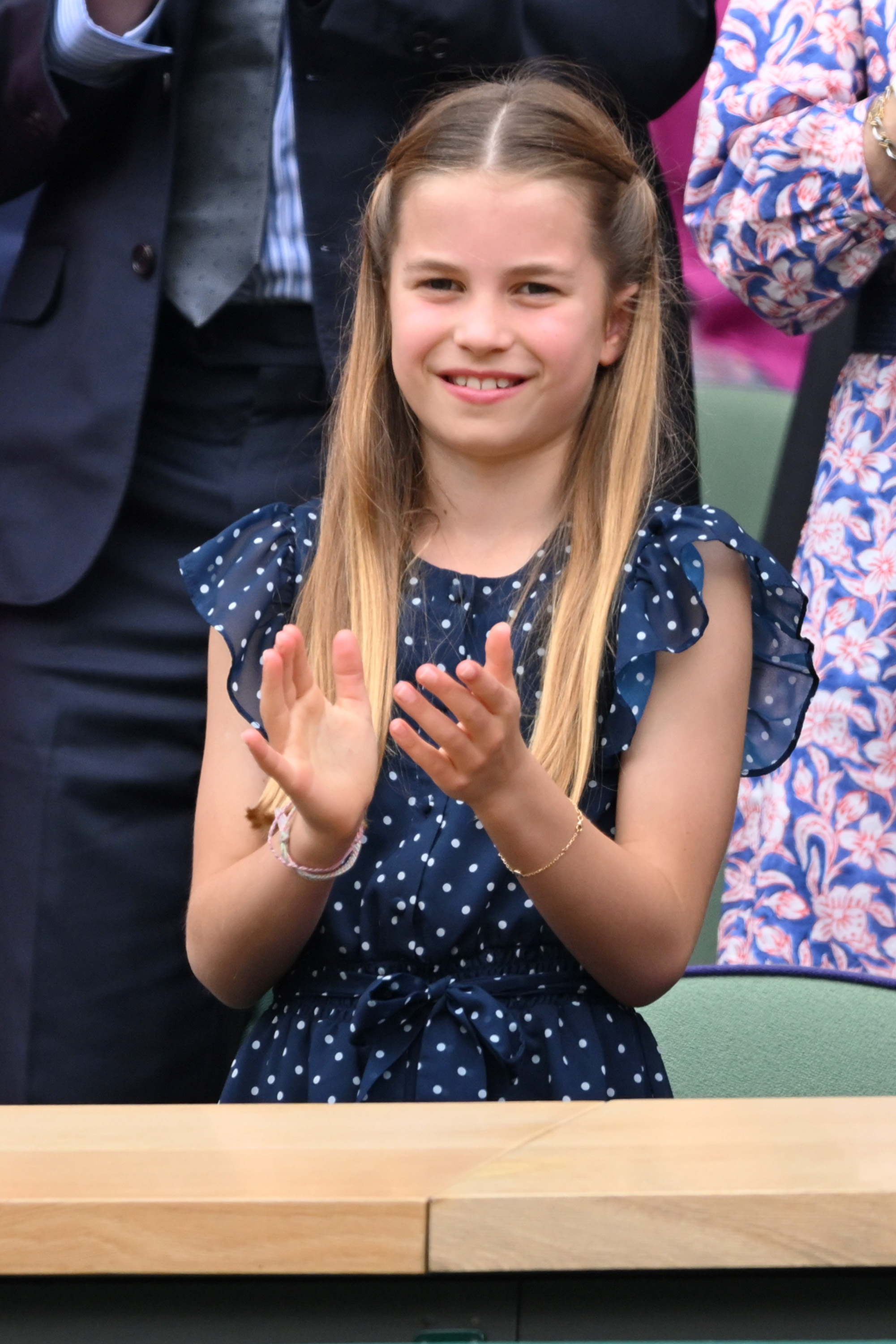 Princess Charlotte wearing a blue polka dot dress, clapping at Wimbledon
