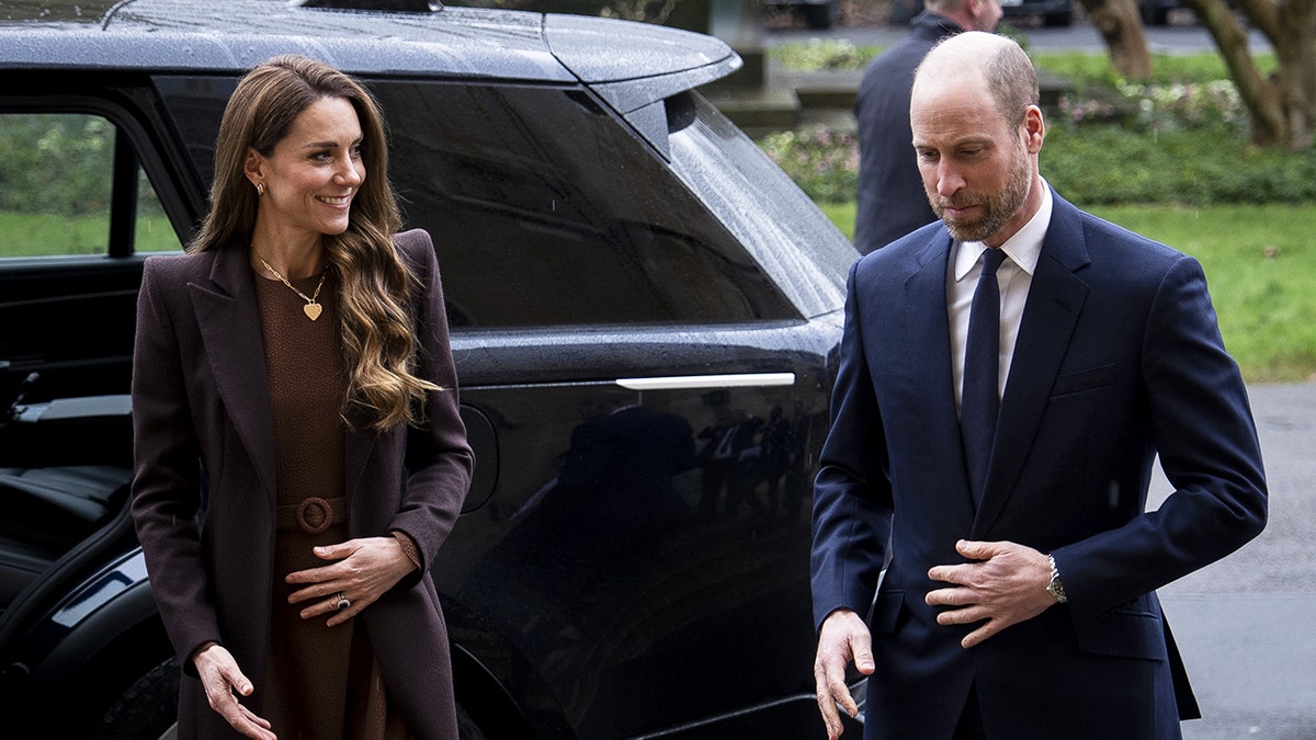 Prince William and Kate Middleton walking together in front of a black car.