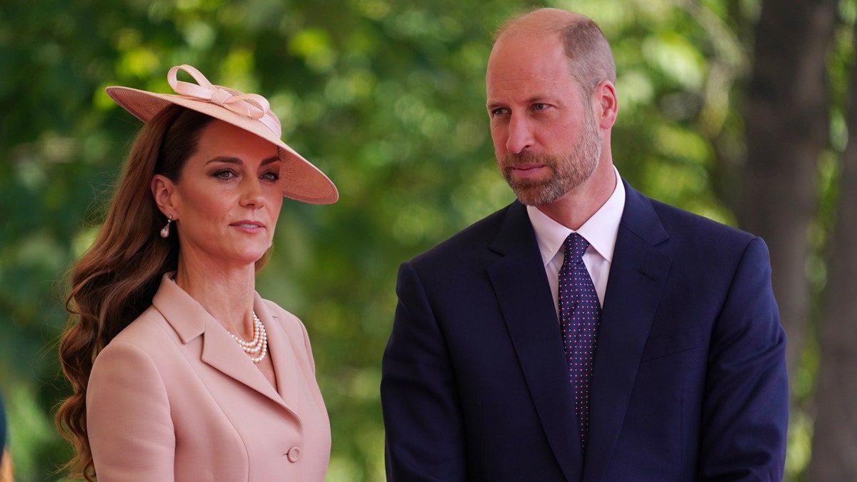 Kate Middleton and Prince William stand in front of greenery