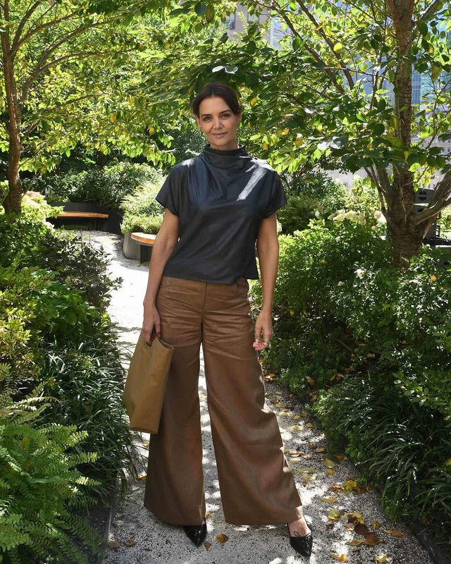 person standing in a lush garden with greenery and modern buildings in the background
