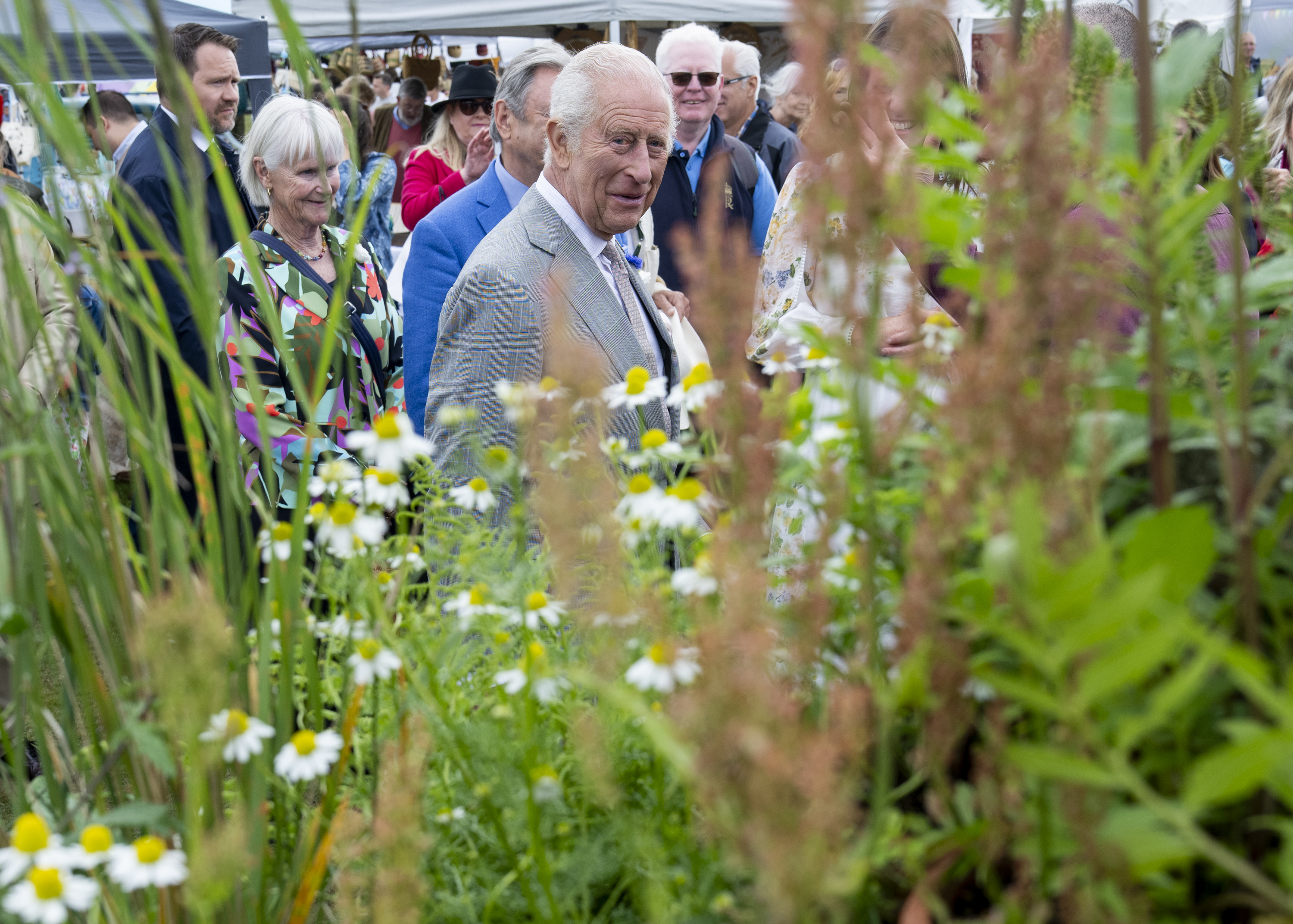 King Charles standing in a garden