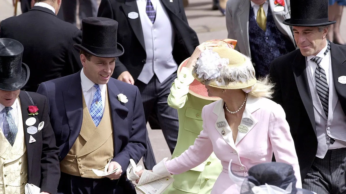 Prince Andrew in a suit and top hat looking at a woman wearing a light pink suit and floral hat as Jeffrey Epstein looks on.