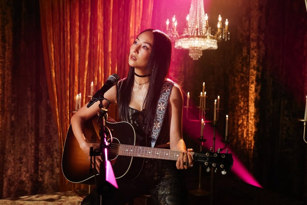a musician performing with an acoustic guitar in a dimly lit setting