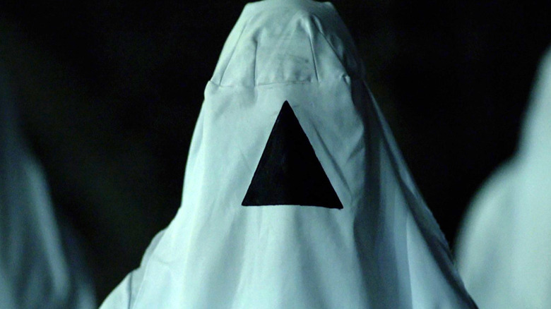 A person wearing a white hood with a black triangle in 