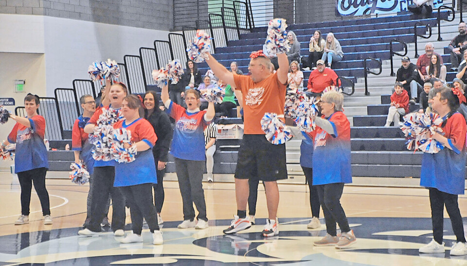 Cheerleaders performing with pom-poms in a gymnasium.