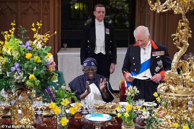 President of Nigeria Bola Ahmed Tinubu claps in his seat between Princess Kate and King Charles III, who is making a speech