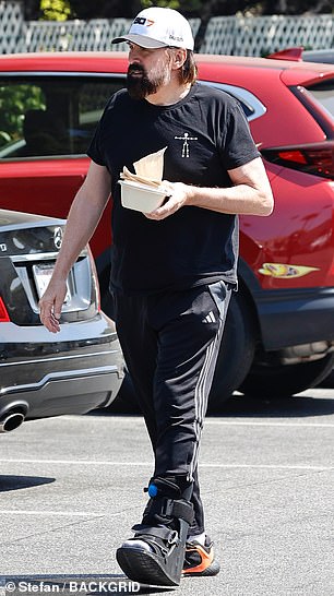 He sported a short-sleeved, black shirt as well as a pair of black Adidas track pants and a white cap