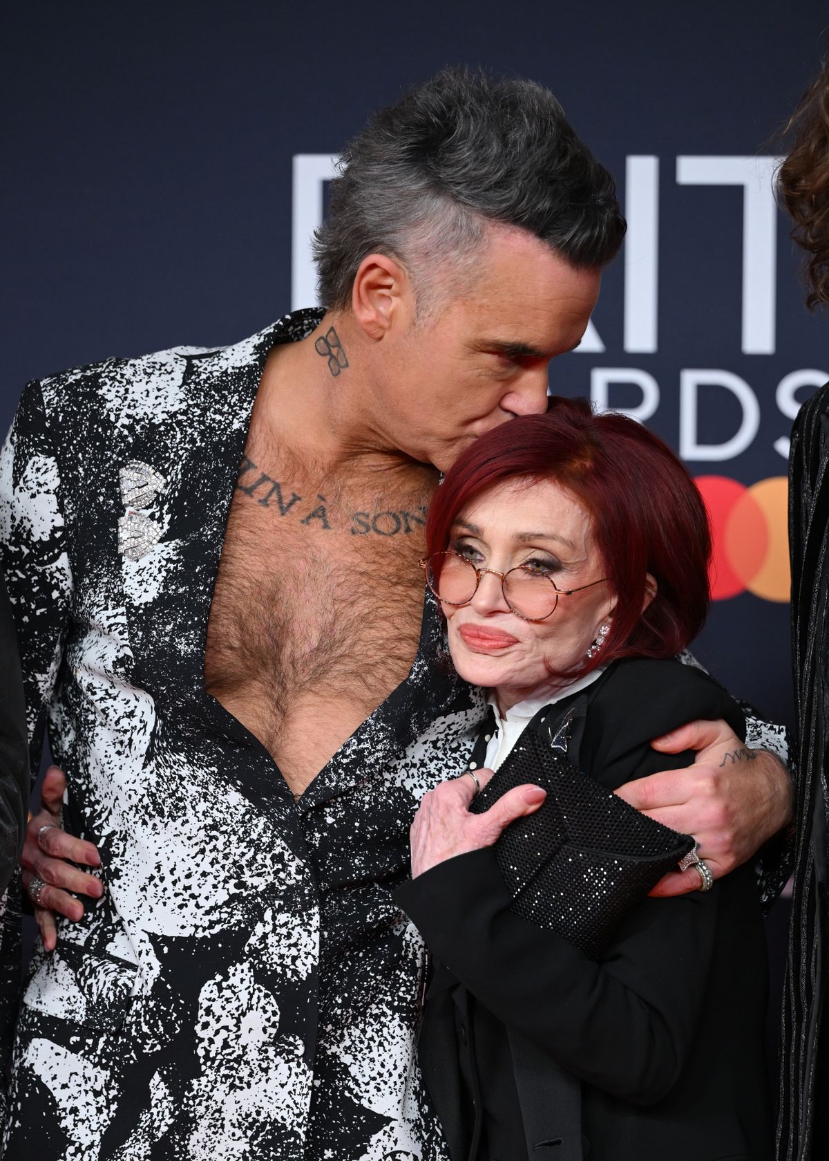 Robbie kisses Ozzy's widow Sharon Osbourne as they arrived at last night's Brit Awards 