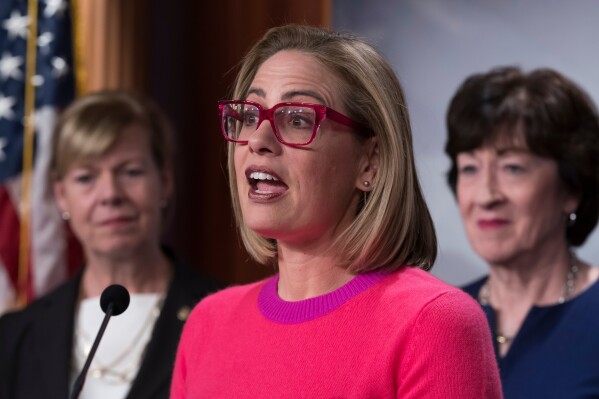 Sen. Kyrsten Sinema, D-Ariz., flanked by Sen. Tammy Baldwin, D-Wis., left, and Sen. Susan Collins, R-Maine, speaks to reporters following Senate passage of the Respect for Marriage Act, at the Capitol in Washington, Nov. 29, 2022. (AP Photo/J. Scott Applewhite, File)