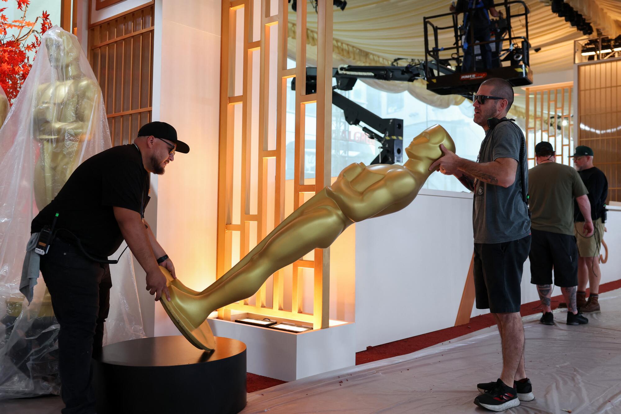Workers move a decorative Oscar statue