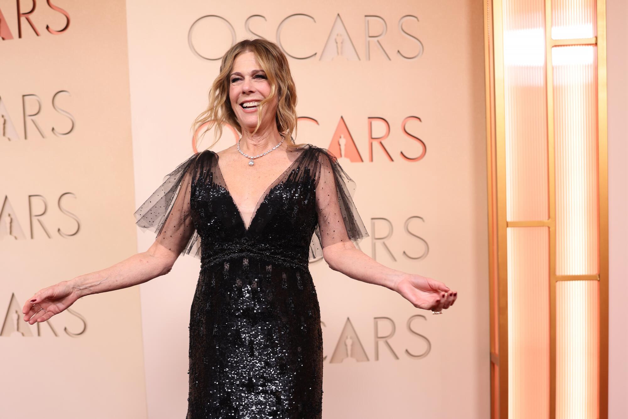 Rita Wilson, wearing a black gown, poses on the red carpet. 