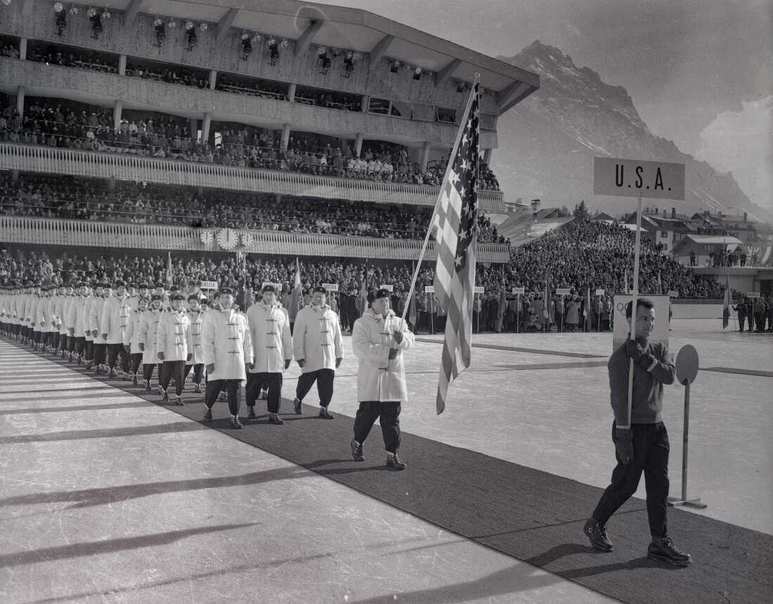 Members of the United States Olympic teams are shown during the colorful procession into Cortina's huge ice stadium for opening ceremonies launching 11 days of competition in the Winter Olympics. Marching in alphabetical order by nations the U.S. came in at 26th and received an enthusiastic welcome.