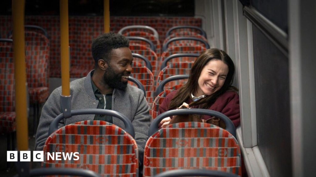 Paapa Essiedu and Siobhán Cullen sitting on the bus and laughing