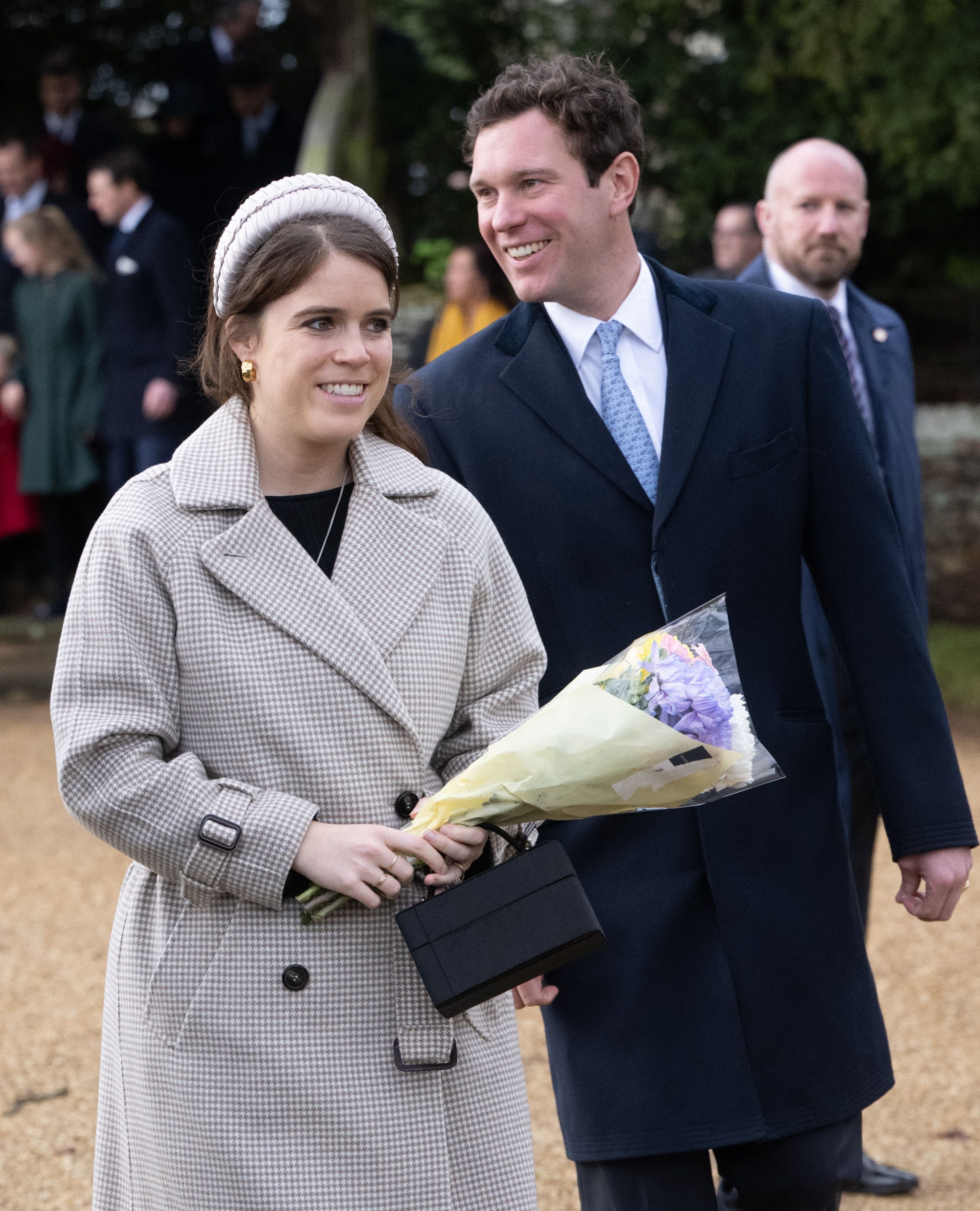 Princess Eugenie holding a bouquet of flowers walking with Jack Brooksbank