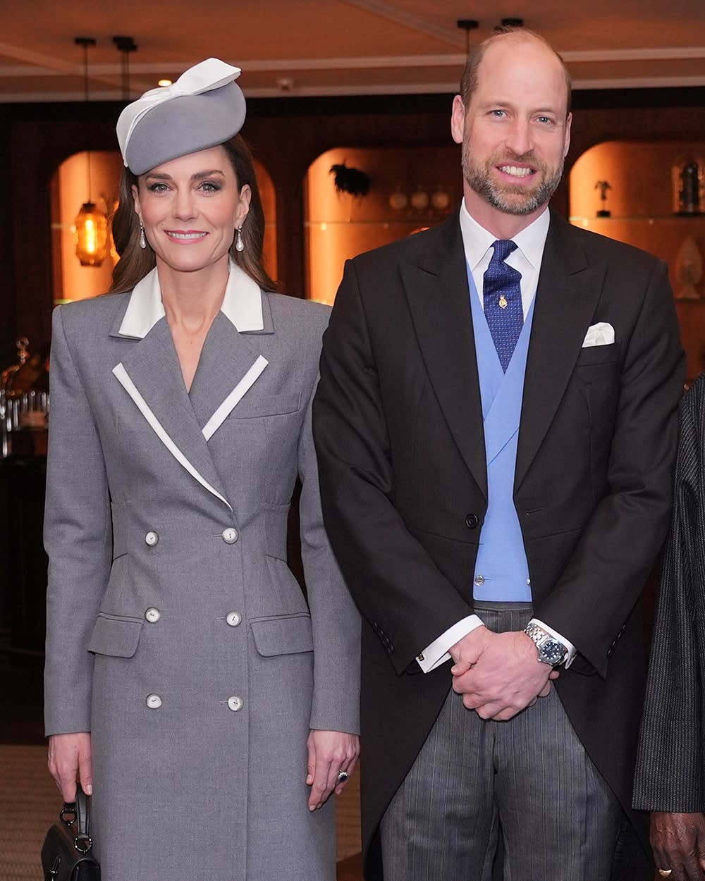 The Prince and Princess of Wales standing shoulder to shoulder smiling in formal wear.