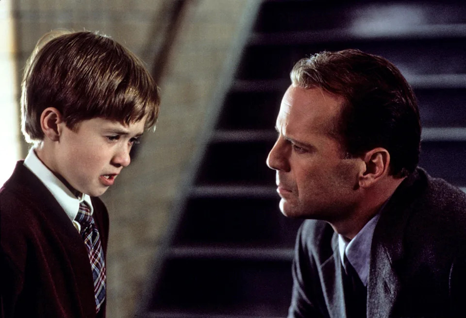 Child and adult having a serious conversation on a staircase, both in formal attire. Image is from a movie scene