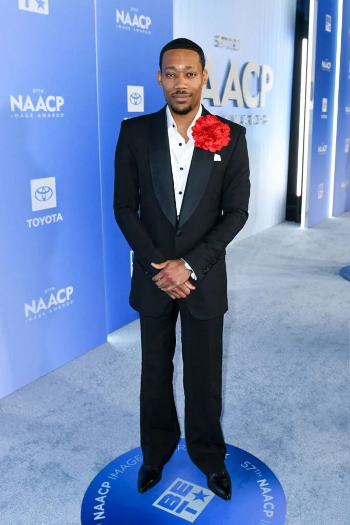 Tyler James Williams, Tyler James Williams Sergio Hudson, Sergio Hudson black suit, Tyler James Williams NAACP Image Awards 2026, red floral lapel detail, Blancpain Villeret Squelette 8 Jours, Tyler James Williams red carpet style, NAACP Image Awards mens tailoring
