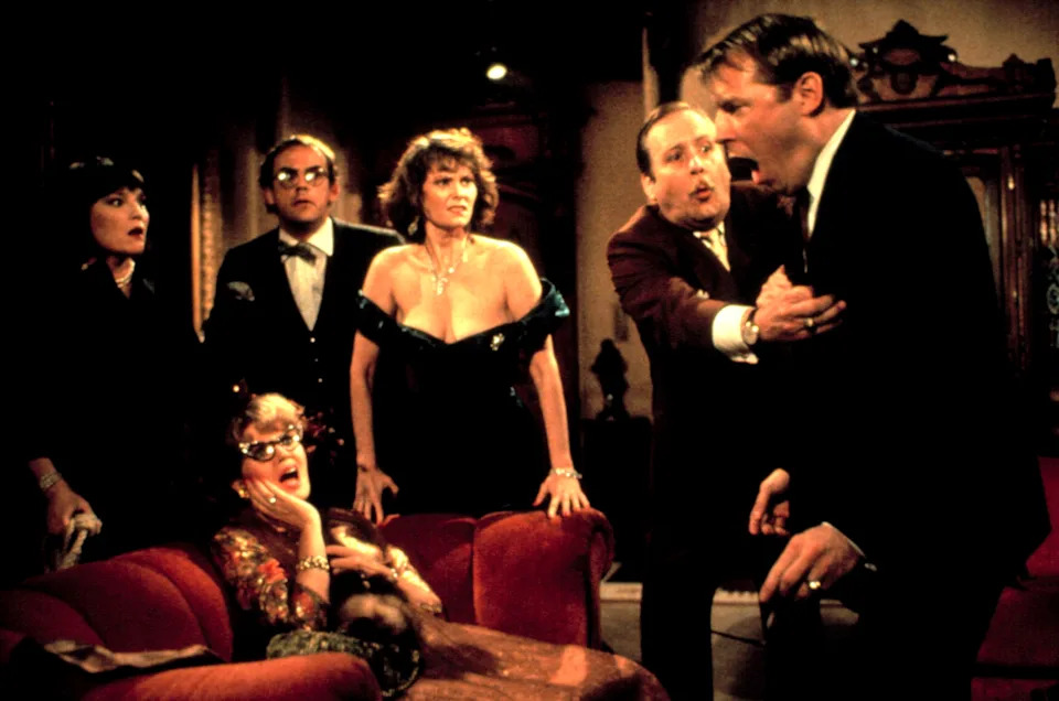 Characters from a classic mystery film express shock and concern in a dramatic living room scene