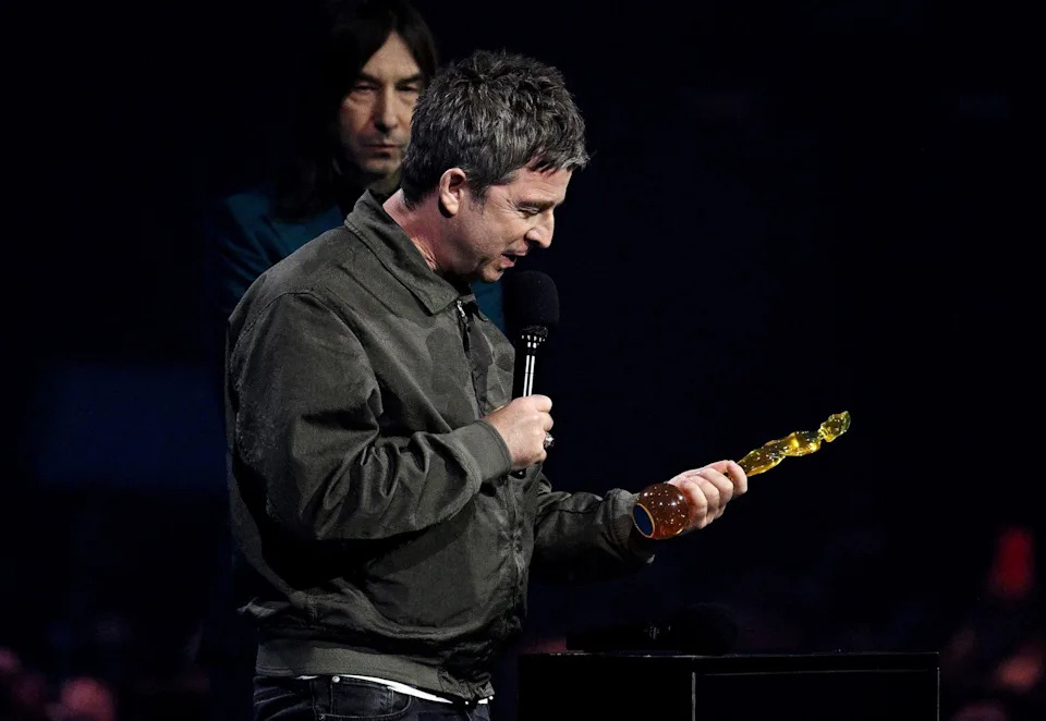 Noel Gallagher dressed in black looks at his award.