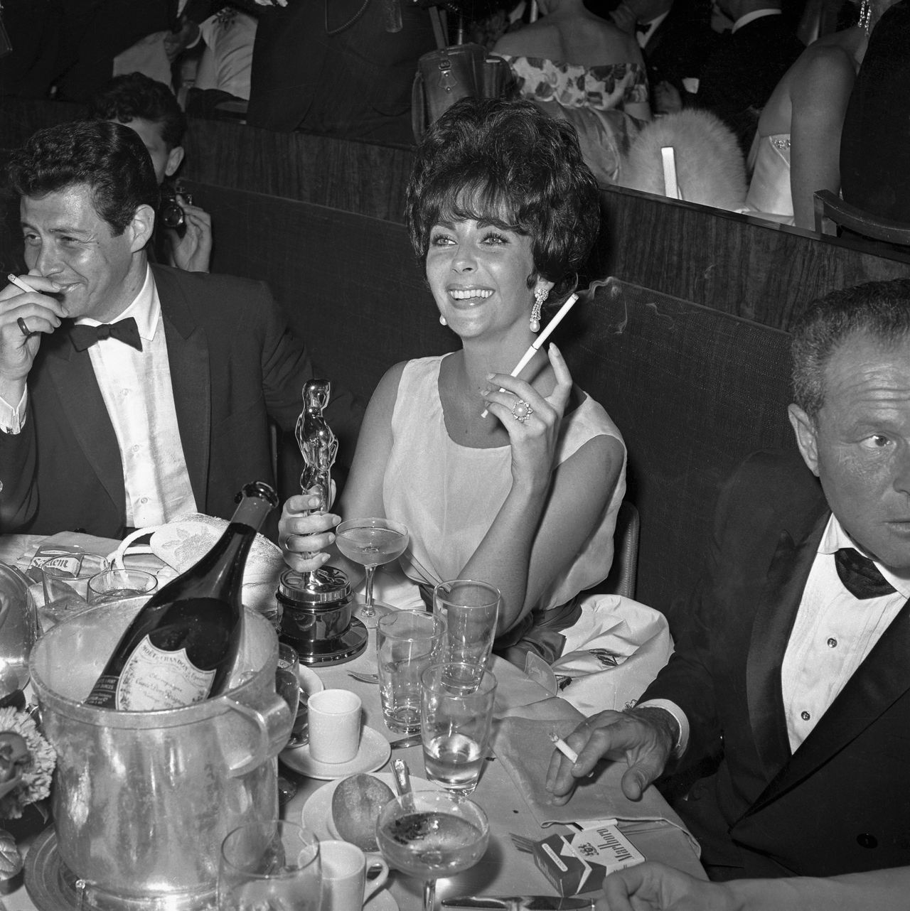 Image may contain: Elizabeth Taylor, Glass, Head, Person, Face, Adult, Smoke, Body Part, Finger, Hand, and Clothing