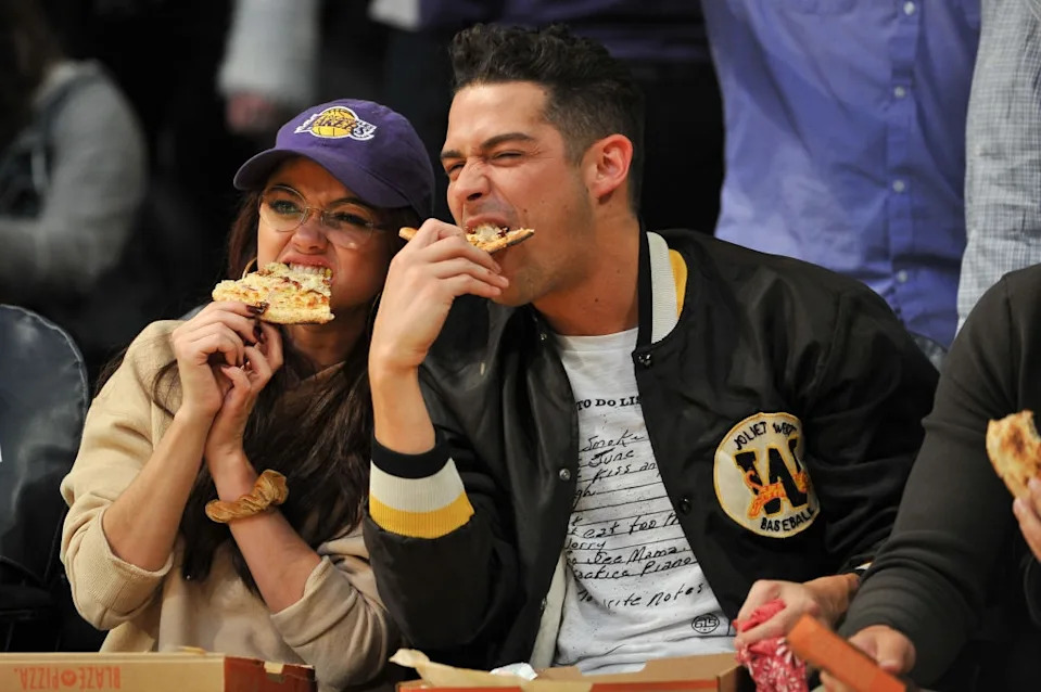 A couple enjoys pizza together at a sports event, smiling and relaxed, fostering a sense of connection and shared enjoyment