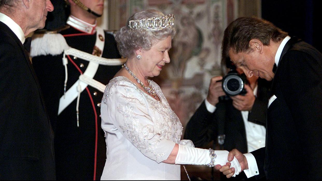 Britain's Queen Elizabeth (C) together with Prince Philip (L) shakes hands with fashion designer Valentino (R) at Quirinal presidential palace before the state banquet with Italian President Carlo Azaglio Ciampi in Rome, Italy.