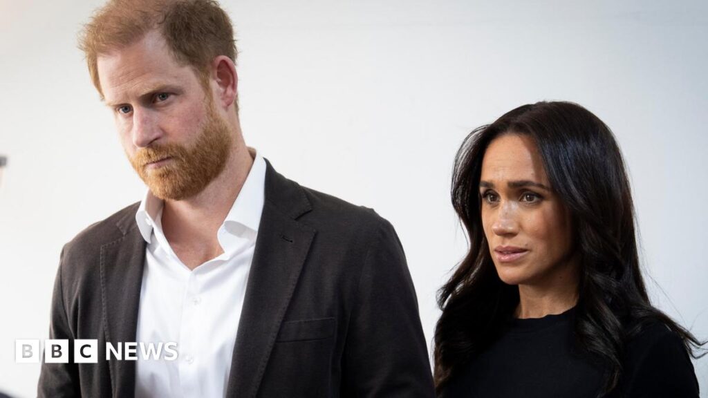 Harry and Meghan accuse royal author of ‘deranged conspiracy’ A montage image, Rachel Reeves is in black and white on the left, and a red treated image of a building lying in ruins in Iran is in the background. A headshot of Laura Kuenssberg with her arms crossed in a pink blazer is to the left.