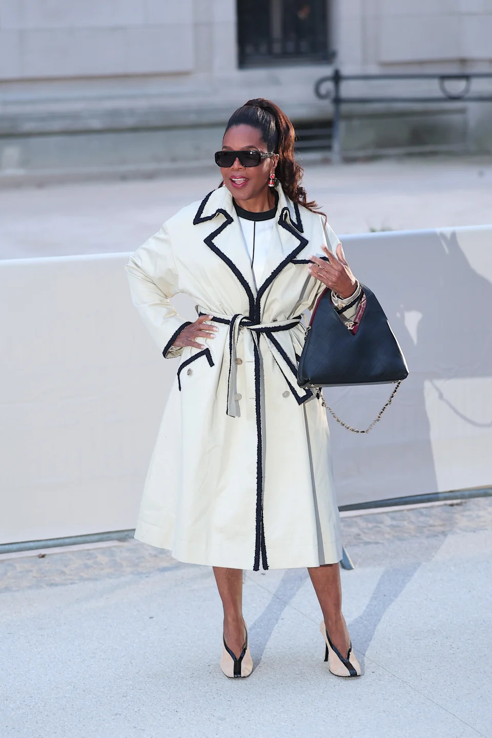 Oprah in a stylish belted trench coat and sunglasses