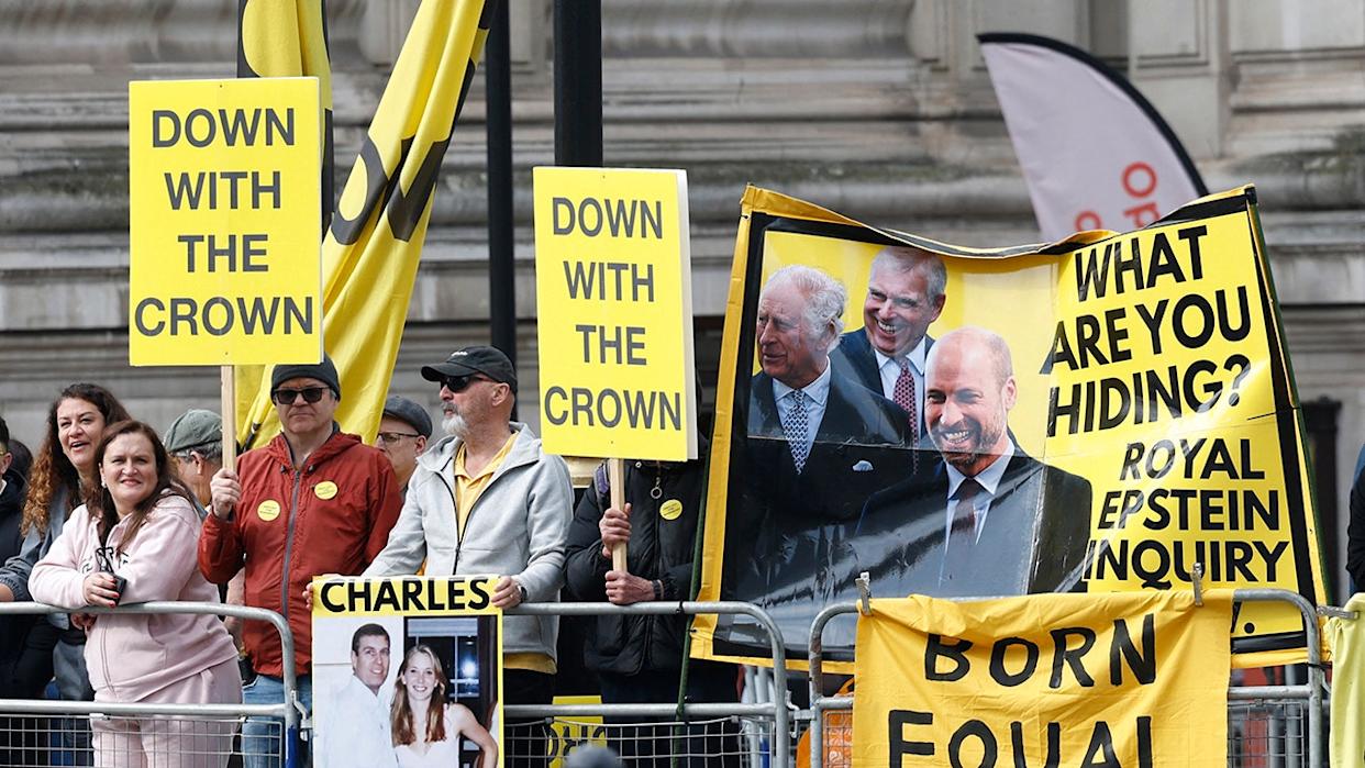 Protest signs that say Down with the crown and What are you hiding?