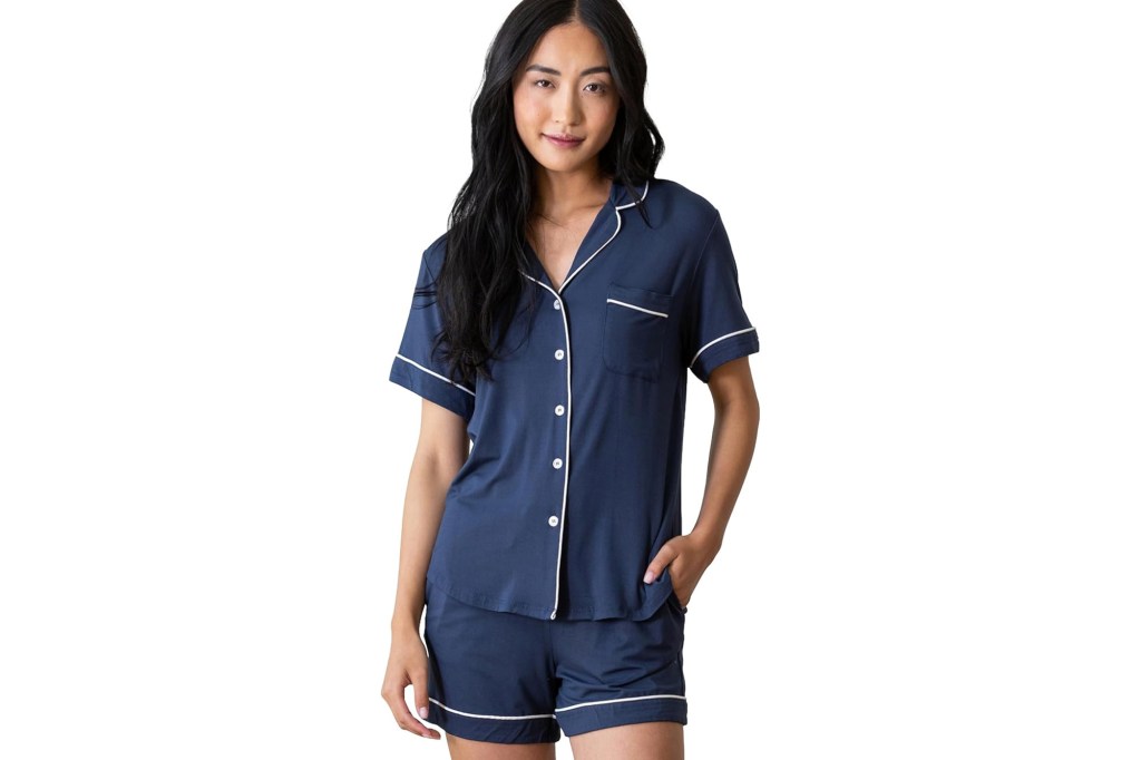 A woman models navy blue short-sleeved pajamas with white piping.