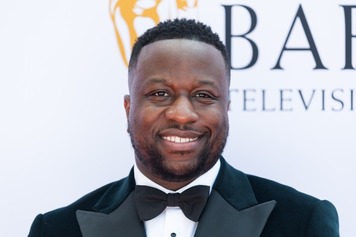 Babatunde Aleshe smiling ahead, wearing a black tuxedo.