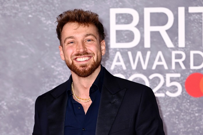 Sam Thompson smiling ahead, wearing a dark coloured suit.