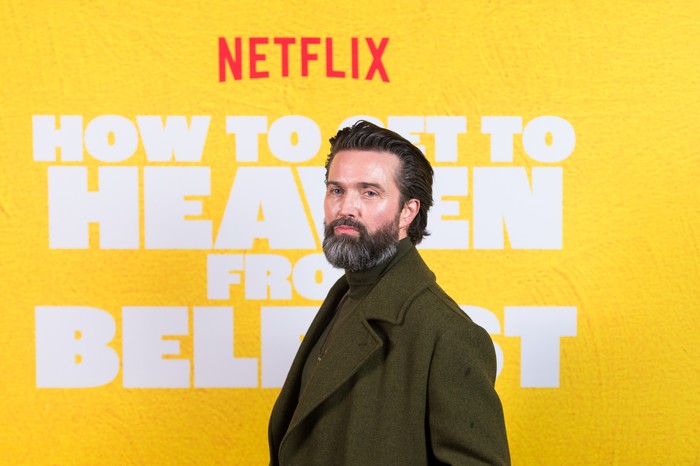 Emmett J Scanlan stood to one side, wearing a large green jacket.
