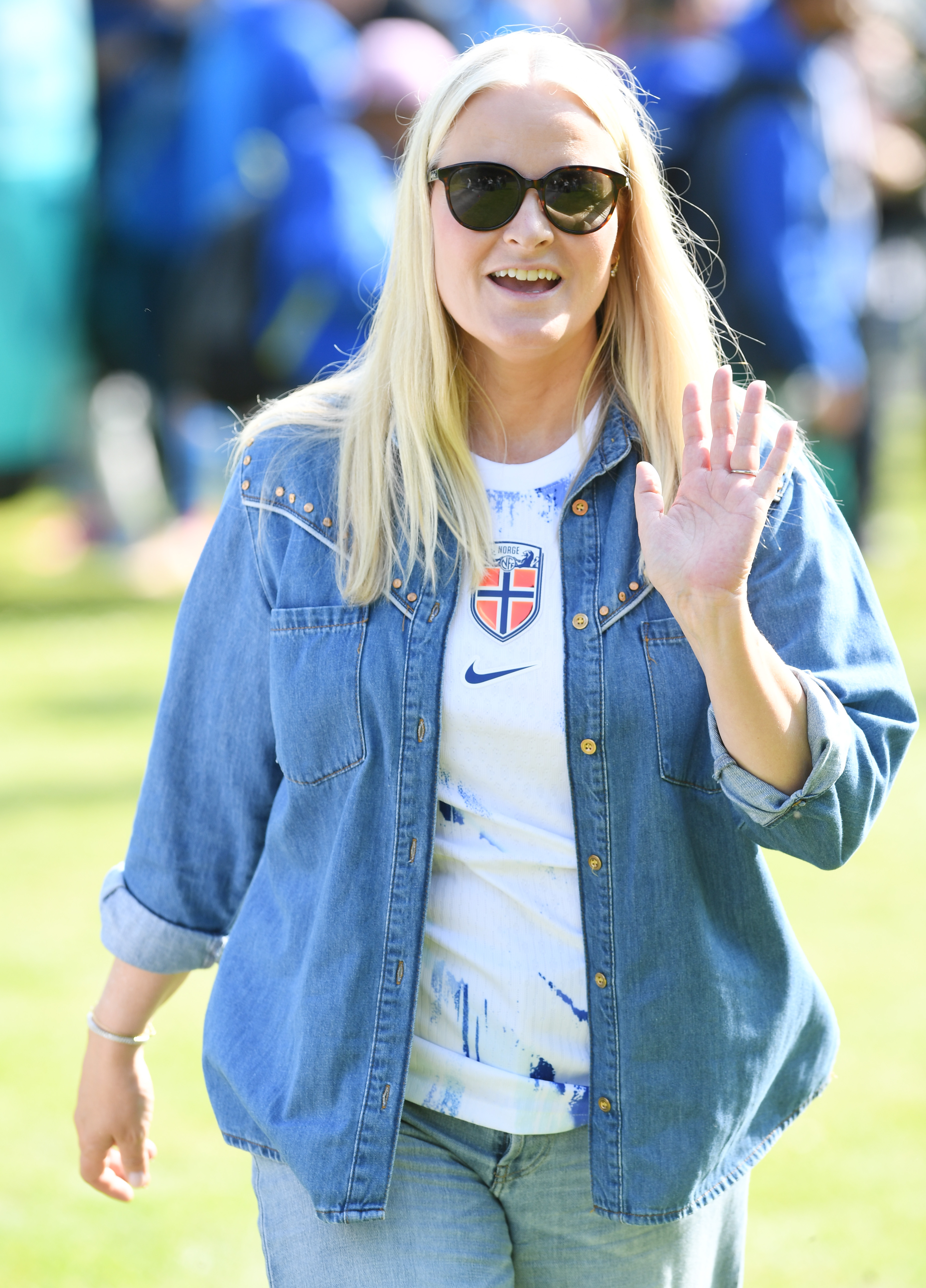 Crown Princess Mette-Marit waving and wearing a denim shirt