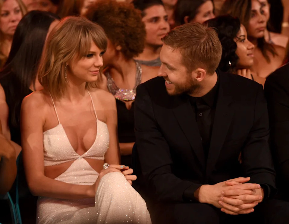 I don't know who these people are, but the image shows a woman in an elegant sleeveless gown and a man in a suit, seated at an event, smiling at each other