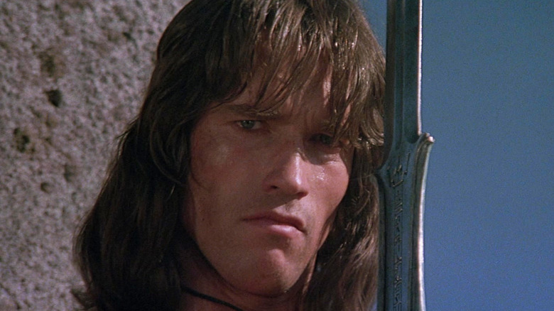 Arnold Schwarzenegger as Conan holding a sword in Conan the Barbarian