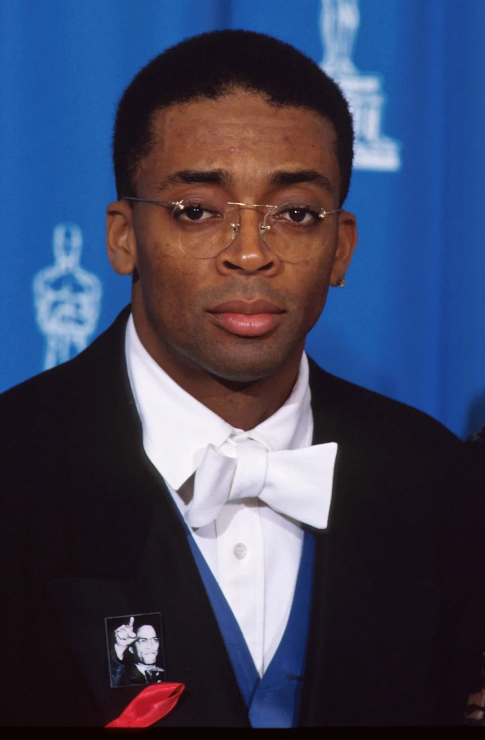 Person in formal attire with glasses and a white bow tie at a prestigious event