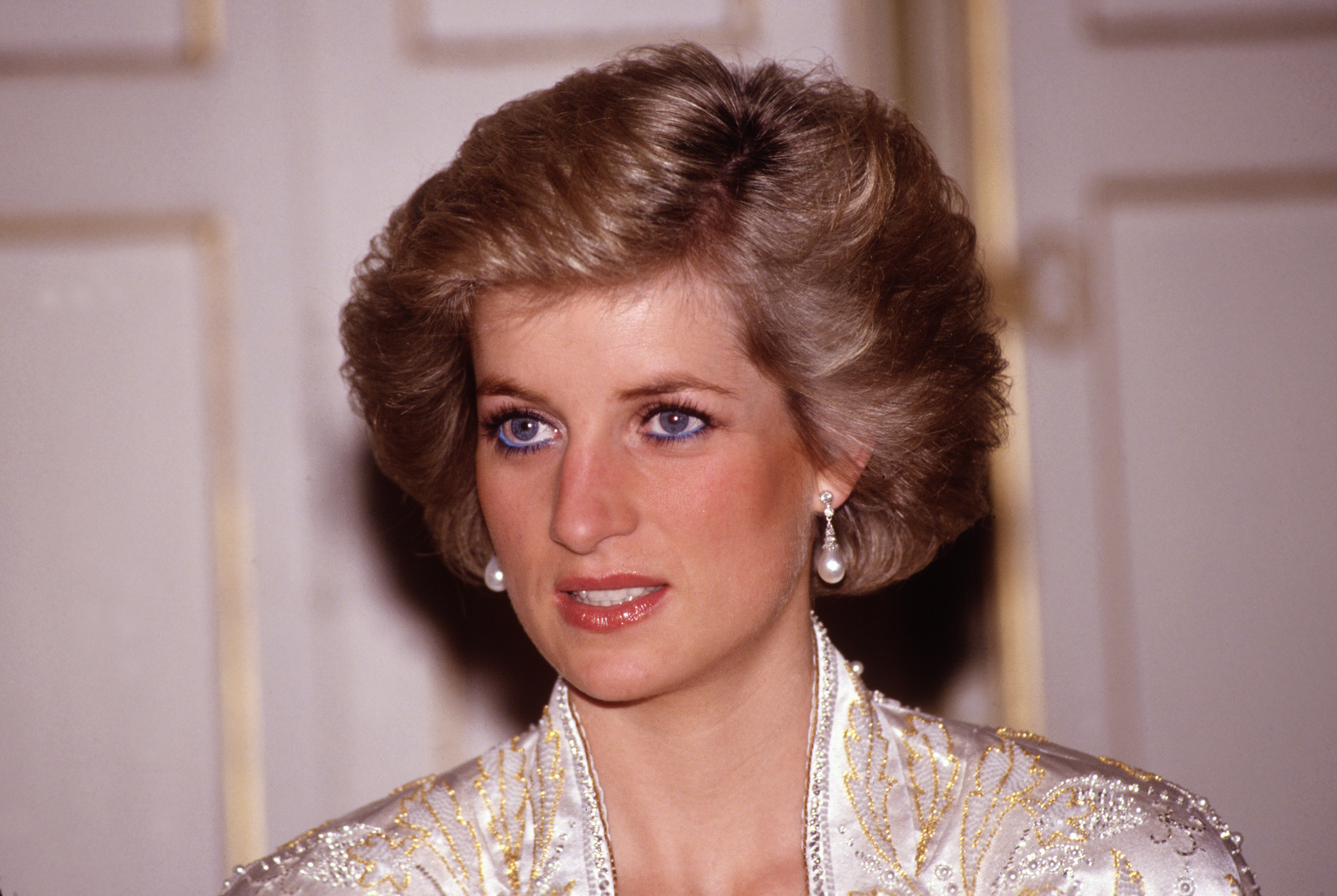 Princess Diana wearing a white dress and pearl earrings
