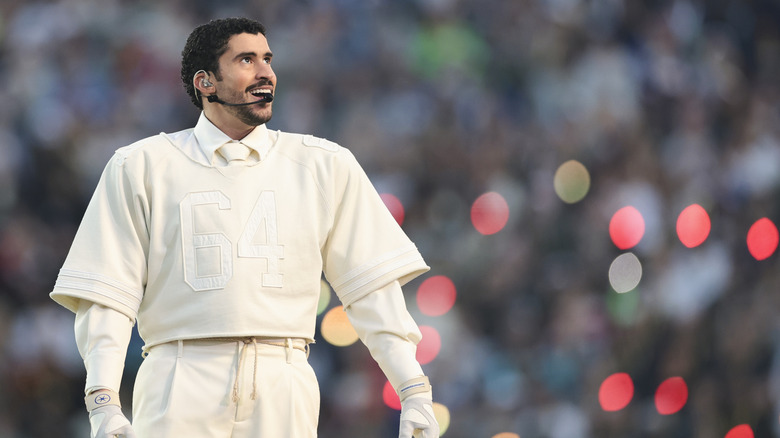 Bad Bunny wearing cream shirt and tie performing on stage