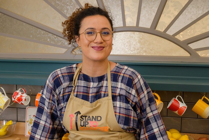 Rose Matafeo smiling ahead wearing a gingham patterned shirt.