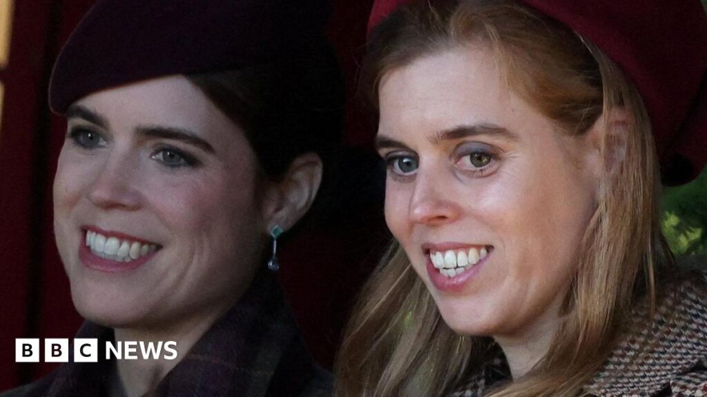 Princesses Eugenie and Beatrice, seen in close-up, smiling and looking off camera - they are both wearing coats and hats