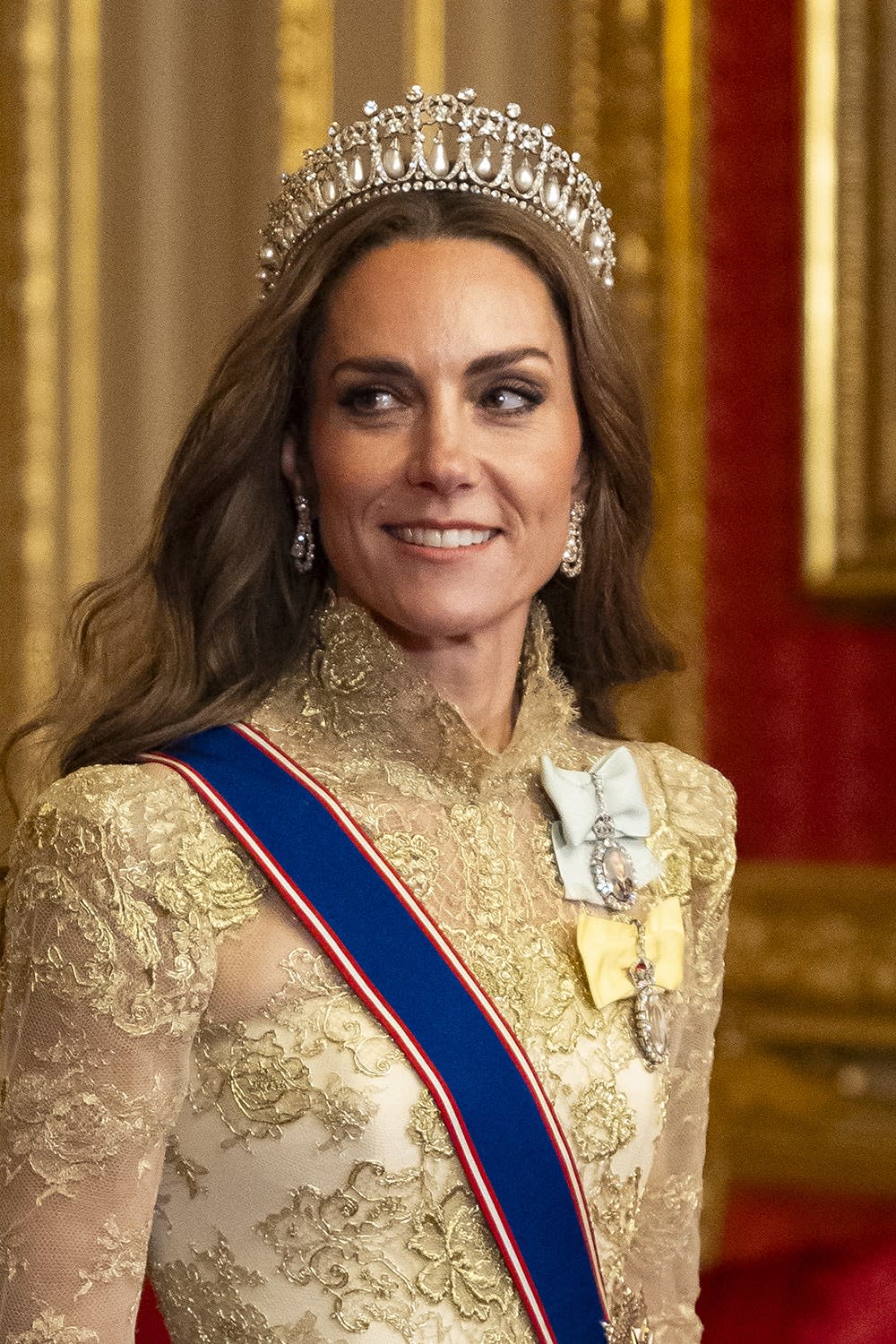 A close-up of Kate Middleton wearing a gold dress and tiara.