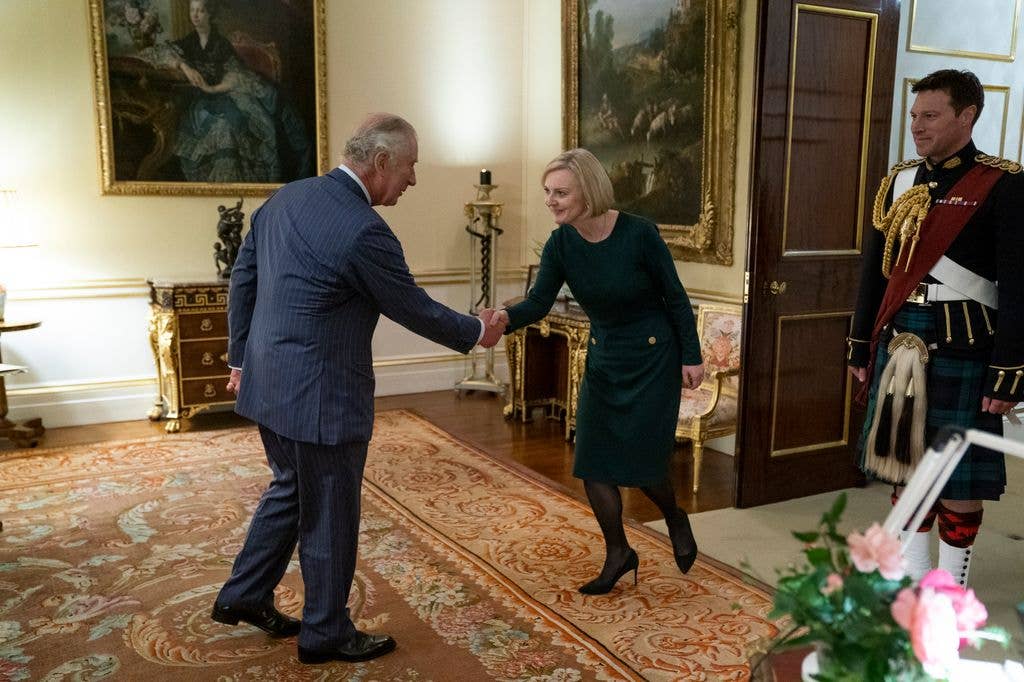 King Charles shaking hands with Liz Truss as she curtsies