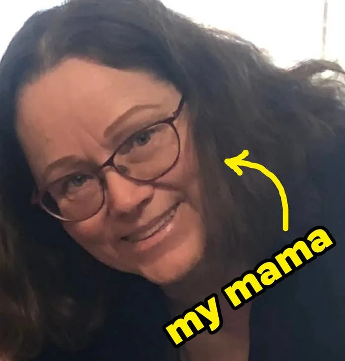 Smiling person with glasses, shoulder-length hair